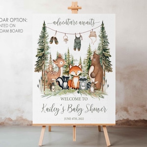 K&ouml;nnte beinhalten: Ein wei&szlig;es Willkommens-Schild mit Waldmotiv. Das Schild zeigt einen Fuchs, ein Reh, einen B&auml;ren und einen Waschb&auml;ren. Der Text auf dem Schild lautet "adventure awaits" und "Welcome to Kailey's Baby Shower June 4th, 2022".