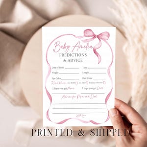 May include: A baby shower prediction and advice card with a pink ribbon design. The card includes prompts for the baby's birth details and advice for the parents. The text "Baby Amelia" is at the top. The words "PRINTED & SHIPPED" are at the bottom.