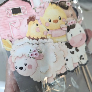 May include: A set of six pink and white farm animal cupcake toppers. The toppers feature a pig, a chick, a sheep, a cow, a barn, and a chick with a pink bow.