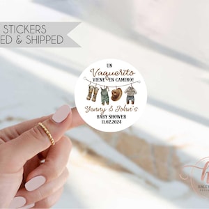 May include: A round sticker with the text "Un Vaquerito Viene En Camino!" and "Yenny & John's BABY SHOWER 11.02.2024". The sticker features illustrations of cowboy boots, overalls, a hat, and a shirt. The sticker is 2 inches in diameter.