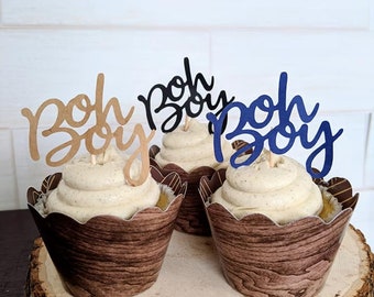 May include: Three cupcakes with brown and white frosting topped with a "boho boy" cupcake topper in black, gold, and blue.