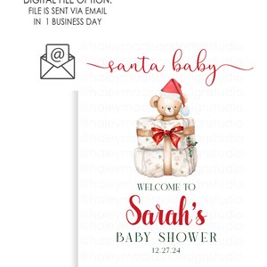 May include: A rectangular sign featuring the text santa baby in red script, a watercolor illustration of a teddy bear wearing a Santa hat sitting on wrapped gifts, and the text WELCOME TO Sarah's BABY SHOWER 12.27.24 in red and dark green.