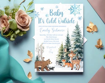 Op de afbeelding: Een uitnodiging voor een babyshower met een winterthema. De uitnodiging bevat de tekst "Baby It's Cold Outside" in blauw, samen met illustraties van sneeuwvlokken, bomen en bosdieren. De uitnodiging bevat evenementdetails.