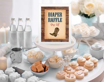Op de afbeelding: Een wit ingelijst bord met een rustieke houten achtergrond en de tekst "Diaper Raffle Drop Off" in blauwe en rode letters. Onder de tekst is een bruine cowboylaars met een rode sporen afgebeeld. Het bord staat op een witte taartstandaard met verschillende desserts op een witte tafel.