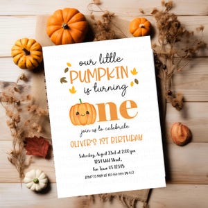 May include: A white invitation card with the text "our little PUMPKIN is turning ONE" and "join us to celebrate OLIVER'S 1ST BIRTHDAY". The card features a smiling pumpkin illustration and is surrounded by small pumpkins and fall foliage.