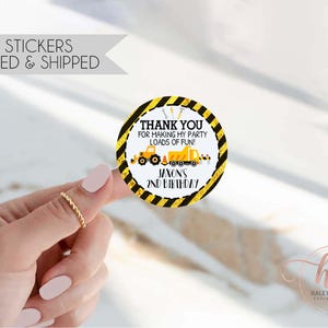 May include: Round yellow and black construction themed thank you stickers with the text "Thank you for making my party loads of fun! Jaxon's 2nd Birthday".