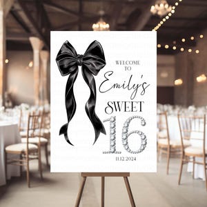 Może przedstawiać: Biały znak powitalny z czarną kokardką, tekstem "Witamy na Emily's Sweet 16" i datą "11.12.2024".