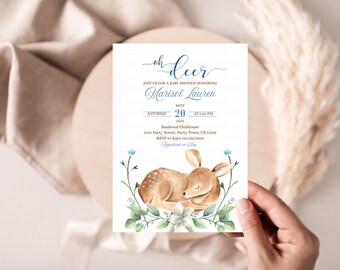 May include: Baby shower invitation with the text "Oh Deer" in blue script. The invitation features a watercolor illustration of a sleeping fawn surrounded by flowers and greenery. The invitation includes the name "Marisol Lauren", date, time, and location.