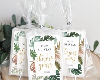 May include: Three white favor boxes with green and brown tropical leaf designs and gold lettering. The boxes have labels that say "From Olivia's Shower to Yours" with the date "11.22.2020".
