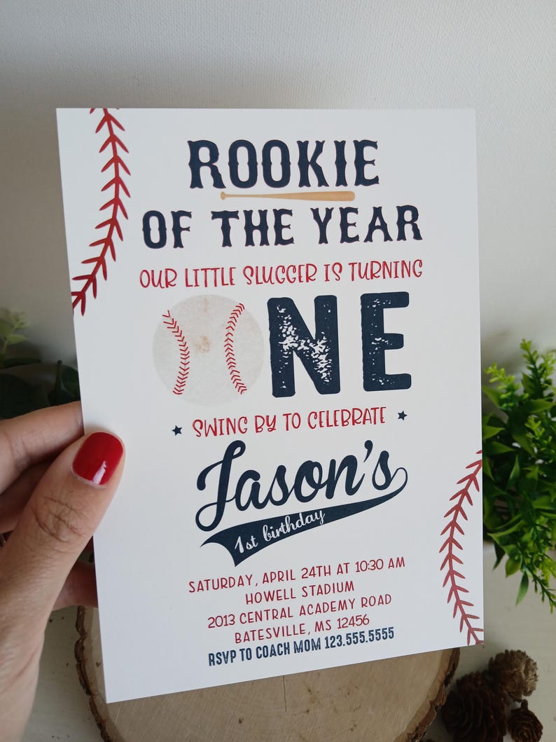 K&ouml;nnte beinhalten: Eine Baseball-Motto-Einladung zum ersten Geburtstag mit roten und blauen Akzenten. Die Einladung zeigt eine Baseball-Grafik und den Text "Rookie of the Year" und "Our little slugger is turning one". Die Einladung enth&auml;lt auch den Namen "Jason's" sowie Datum und Uhrzeit der Party.