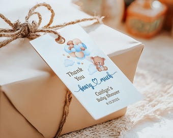 May include: A gift tag with a teddy bear illustration and the text "Thank You beary much". The tag is attached to a wrapped gift with twine. The tag also includes the text "Caitlyn's Baby Shower 9.12.2025".