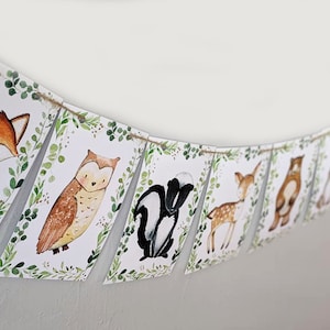 May include: A woodland animal themed banner with a fox, owl, skunk, deer, bear, and squirrel. Each animal is illustrated in a watercolor style on a white background with green foliage.