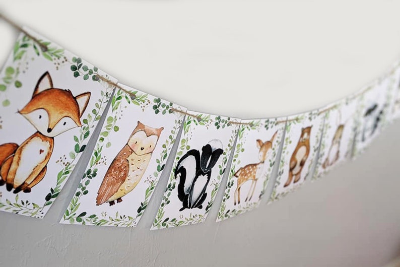 May include: A woodland animal themed banner with a fox, owl, skunk, deer, bear, and squirrel. Each animal is illustrated in a watercolor style on a white background with green foliage.