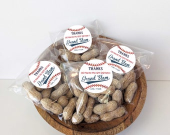 May include: A wooden bowl filled with clear bags of peanuts. Each bag has a round sticker with baseball-themed text that reads "THANKS FOR MAKING MY FIRST BIRTHDAY A GRAND SLAM" and "LOVE, TYSON" in red and blue.