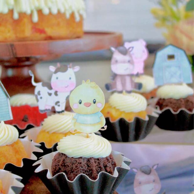 May include: A close-up of cupcakes decorated with farm animal toppers. The cupcakes are in black and white paper cases. The toppers include a cow, a chick, a horse, and a pig.