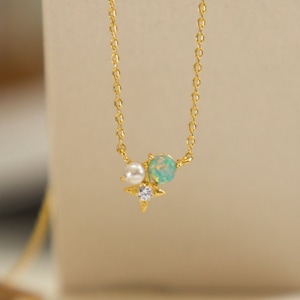 May include: A gold chain necklace with a small star charm, a white pearl, and a light blue opal gemstone.