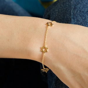 May include: A gold chain bracelet with a series of small, open star of David charms.