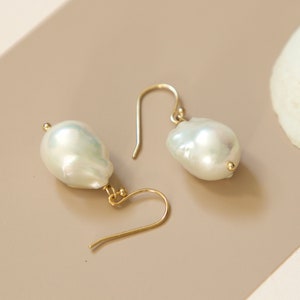 May include: A pair of gold earrings with large, white baroque pearl drops.