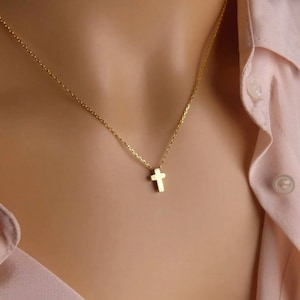 Puede incluir: Un delicado collar de cadena dorada con un peque&ntilde;o colgante de cruz simple.
