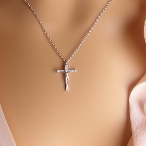 Puede incluir: Un collar de cadena de plata con un peque&ntilde;o colgante de crucifijo de plata.