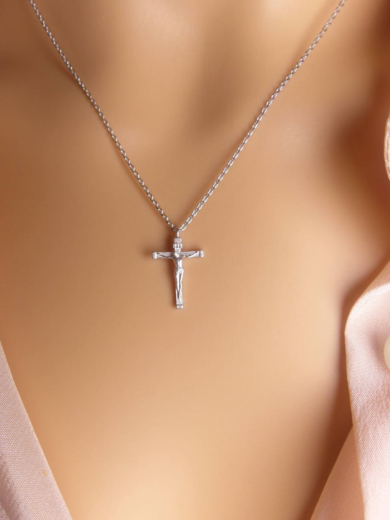 Puede incluir: Un collar de cadena de plata con un peque&ntilde;o colgante de crucifijo de plata.