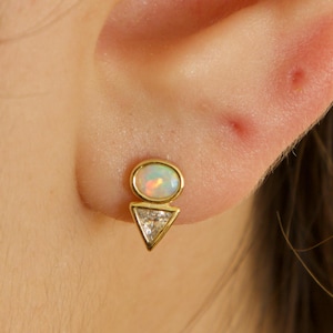 Puede incluir: Pendientes de oro con una piedra de ópalo blanco y un acento de diamante en forma de triángulo.