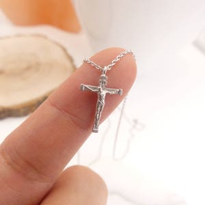 Puede incluir: Un collar de cadena de plata con un peque&ntilde;o colgante de crucifijo de plata. El crucifijo presenta una representaci&oacute;n detallada de Jesucristo.