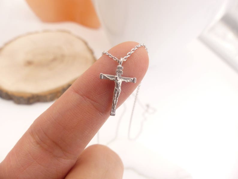 Puede incluir: Un collar de cadena de plata con un peque&ntilde;o colgante de crucifijo de plata. El crucifijo presenta una representaci&oacute;n detallada de Jesucristo.