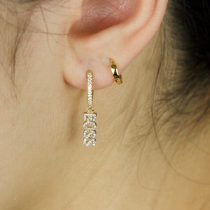 May include: Gold hoop earrings with a dangling charm that says "BOSS" in sparkly rhinestones.