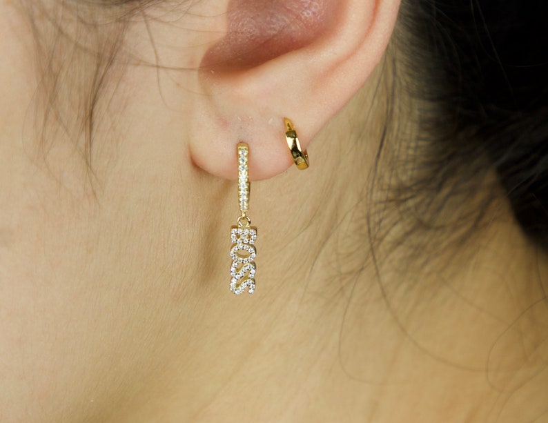 May include: Gold hoop earrings with a dangling charm that says "BOSS" in sparkly rhinestones.