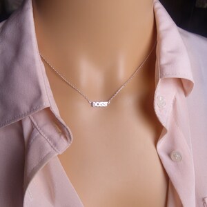 May include: A silver necklace with a delicate chain and a small pendant that says "BOSS" in block letters.