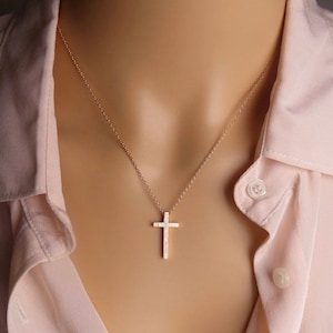 Puede incluir: Un delicado collar de cadena dorada con un peque&ntilde;o colgante de cruz texturizado.