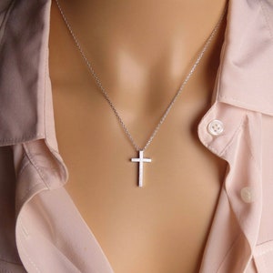 Puede incluir: Un collar de cadena de plata con un peque&ntilde;o colgante de cruz de plata texturizado.