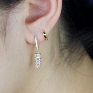 May include: Gold hoop earrings with a dangling charm that says "BOSS" in sparkly rhinestones.