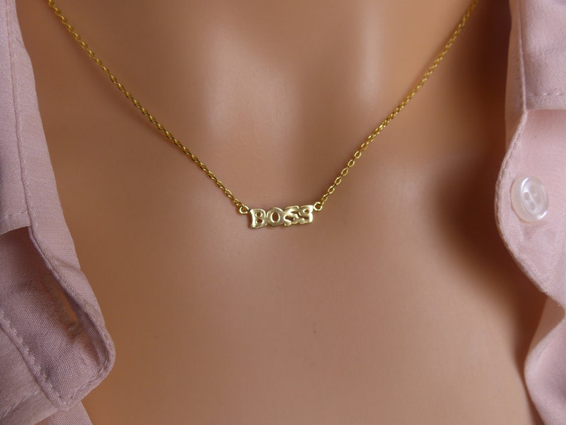 May include: A gold chain necklace with the word "BOSS" spelled out in block letters.