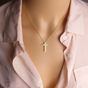 Puede incluir: Un collar de cadena de oro con un peque&ntilde;o colgante de cruz de oro texturizado.