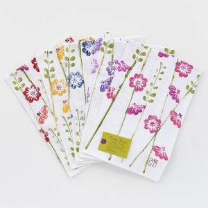 May include: Set of six white tea towels with a floral print. The towels feature a variety of colorful flowers, including pink, purple, yellow, and orange. The towels are made of 100% cotton and are machine washable.