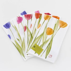 May include: Set of five kitchen towels featuring a watercolor design of colorful tulips. The towels are white with green stems and leaves. The tulips are in shades of purple, pink, red, orange, and yellow. The towels have a label that reads "Pretty Flowers 100% Cotton Tea Towel".
