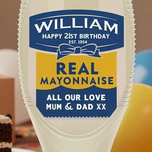 Może przedstawiać: Kremowa butelka majonezu z niebieską i żółtą etykietą. Etykieta głosi "WILLIAM HAPPY 21ST BIRTHDAY EST. 10S4 REAL MAYONNAISE ALL OUR LOVE MUM & DAD XX". Tło zawiera tort urodzinowy, balony i konfetti.