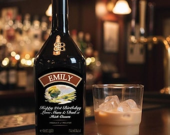 May include: A black bottle of Irish cream with a custom label reading EMILY, Happy 21st Birthday, Love Mum & Dad x, and a glass filled with the beige cream liqueur and ice cubes. The bottle displays a landscape illustration and 700ml volume.