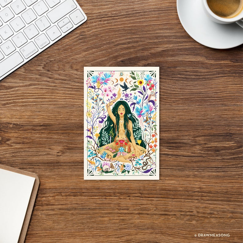 May include: A woman with long green hair sits in a lotus position surrounded by colorful flowers, plants, and animals. She has her arms raised and is holding a crescent moon and a sun. The background is a white rectangle.