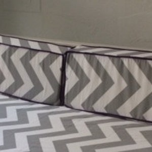 May include: A gray and white chevron patterned daybed with two matching pillows. The pillows have a purple trim.