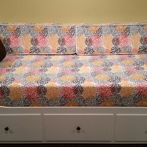 May include: White daybed with three drawers and a floral patterned mattress and pillows. The pillows are brown.