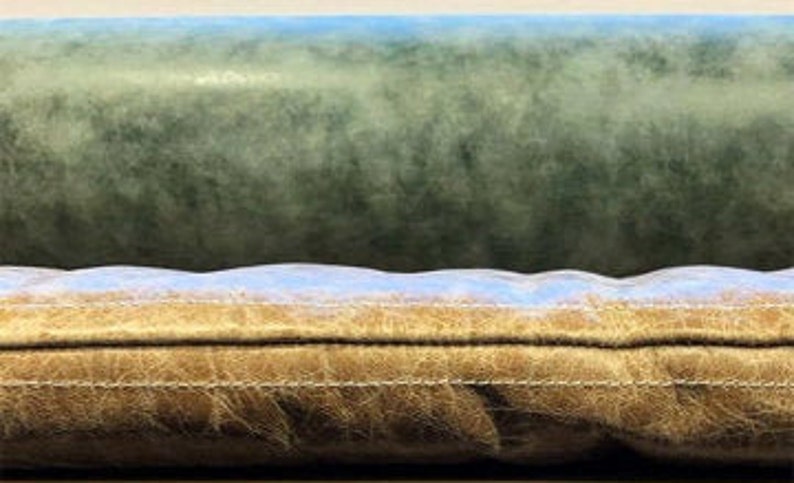 May include: Close-up of a brown leather sofa cushion with a light blue seam and a light blue and green fabric backing.