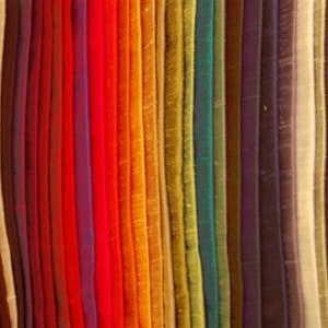 May include: A collection of fabric swatches in various colors, including red, orange, yellow, green, blue, purple, and brown. The fabric is arranged in vertical rows, creating a rainbow effect.