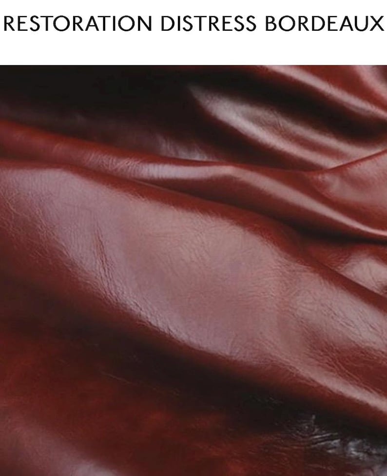 May include: Close-up of a deep red leather with a distressed finish. The leather has a natural grain and a soft, supple texture.