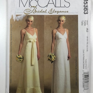 May include: McCall's Bridal Elegance sewing pattern for a white wedding dress with a V-neckline and a bow at the waist. The pattern is for sizes 6-8-10-12-14. The pattern is by Laura Ashley.