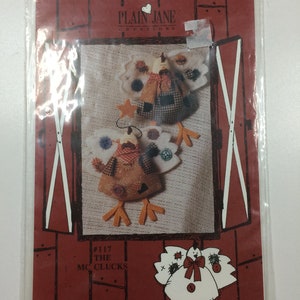 May include: A pattern for making two felt chickens, one brown and one white, with red bows. The pattern is called "#117 The Mc Clucks" and is from Plain Jane Creations.
