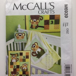 Könnte beinhalten: Ein Nähmuster für eine Babydecke und eine Wandbehänge mit Affen-Motiv. Das Muster enthält Anleitungen zum Nähen von drei verschiedenen Affen-Designs, jedes mit einem anderen Farbschema. Das Muster ist von McCall's Crafts und ist in Größe OSZ.