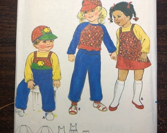 以下が含まれることがあります： 子供服のヴィンテージ裁縫パターン。パターンはサイズ2で、赤と白のギンガムチェックのドレス、青と白のギンガムチェックのシャツ、青いパンツを作るための説明書が含まれています。パターンはバターリック製で、番号は4192です。